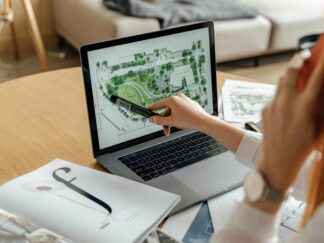 Architect reviewing landscape design on laptop, enhancing architectural projects from home office.